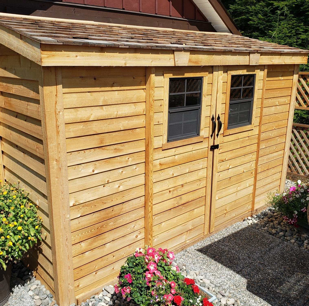 Cedar shed in a compact space with natural wood siding, double doors, windows, and a rustic shingle roof