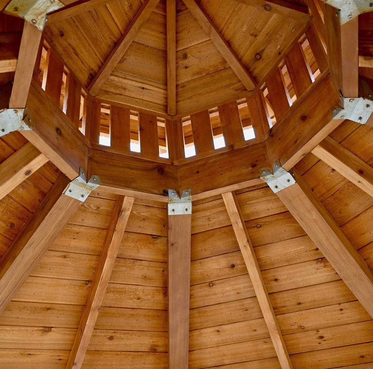 Outdoor Living Today cedar gazebo interior with warm wood panels, exposed beams, octagonal cupola, and metal brackets