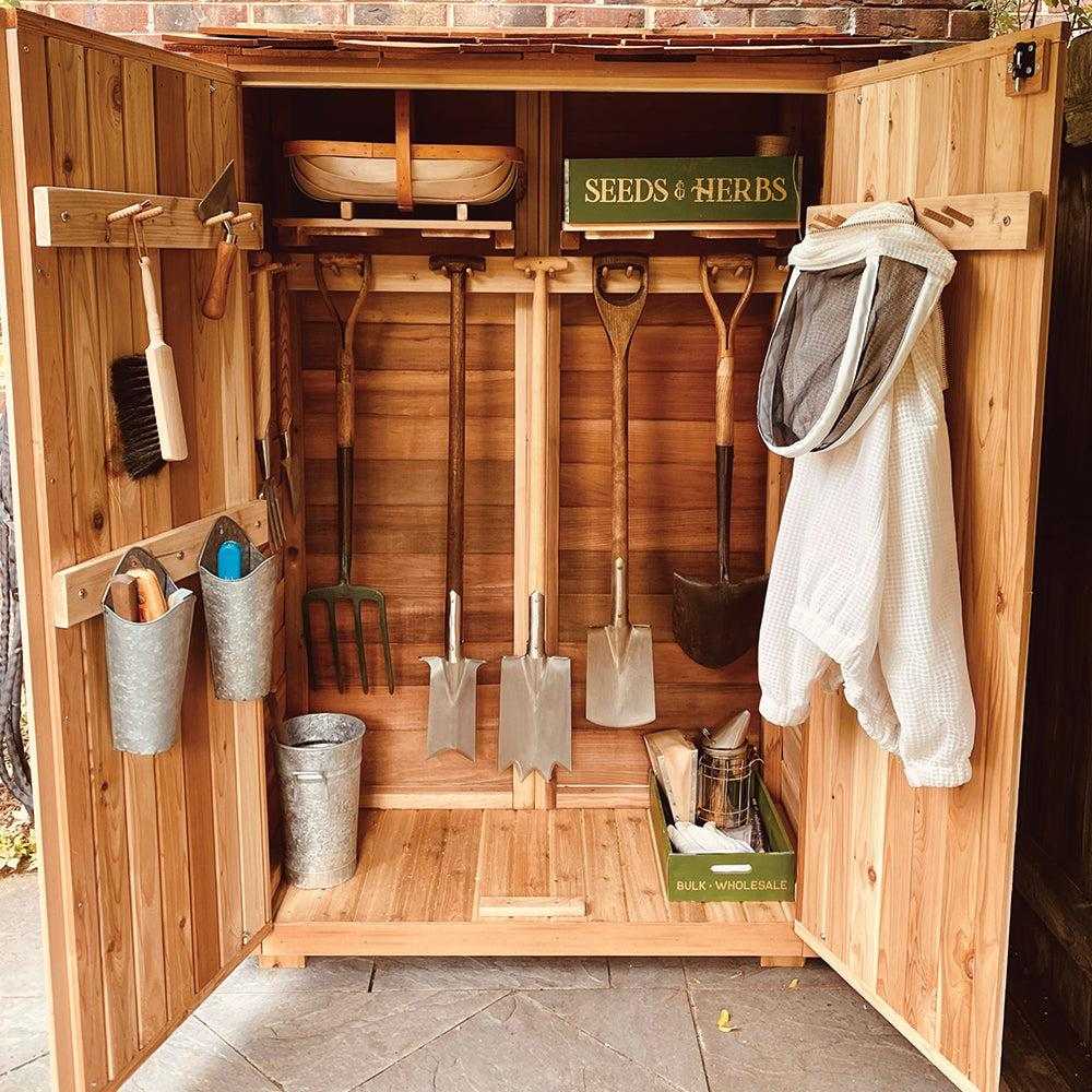 Western Red Cedar Garden Chalet with open double doors showing organized gardening tools, wooden shelves, and storage boxes inside